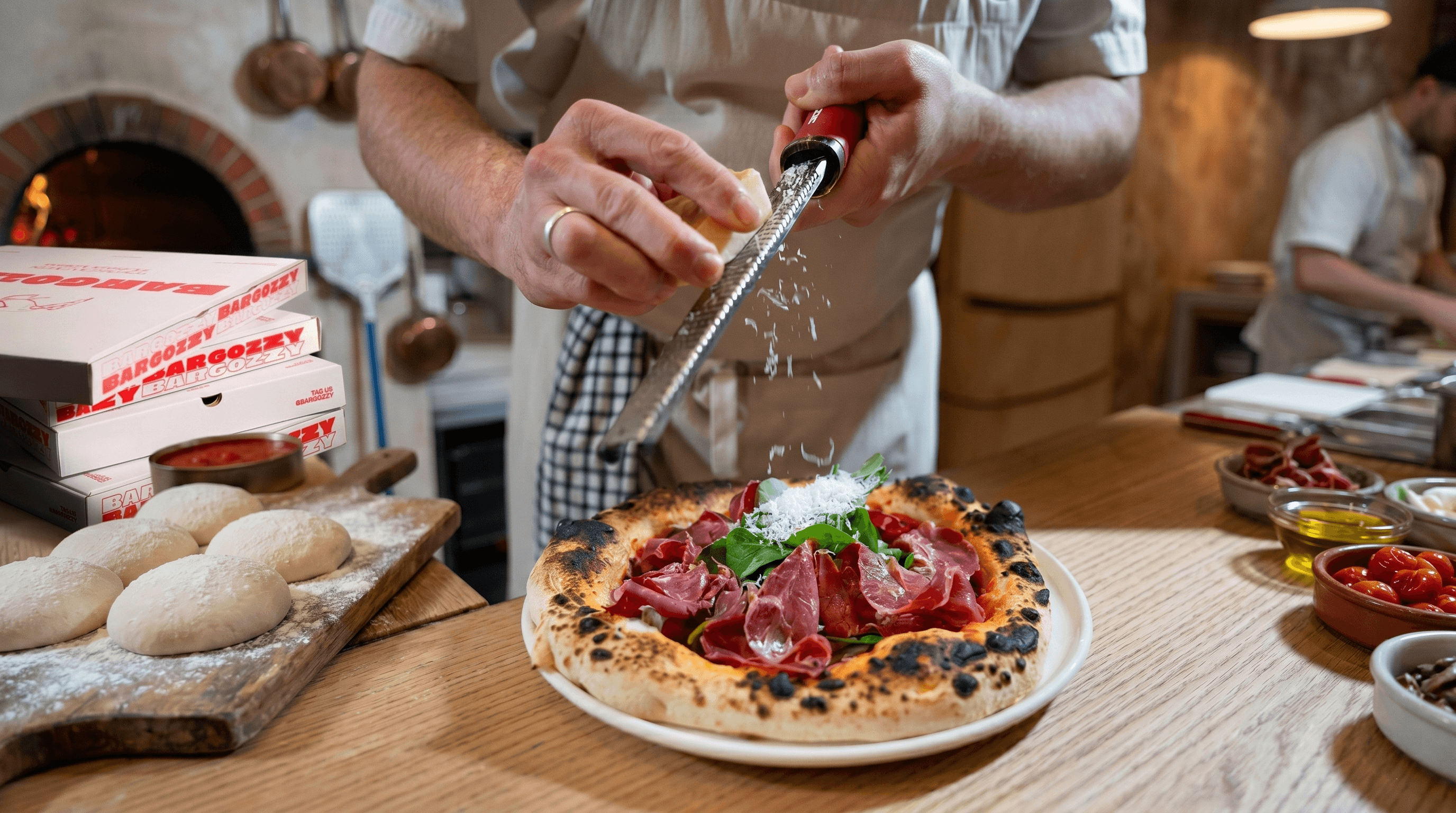 Pizza being finished with grated cheese